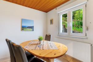 a dining room with a wooden table and two windows at Grüner Ausblick in Oberkirch