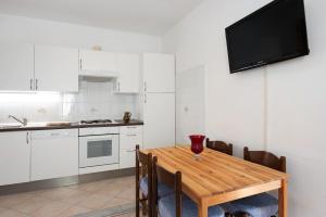 a kitchen with a wooden table and a tv on the wall at Trilocale San Nazario in Varazze +17 photos