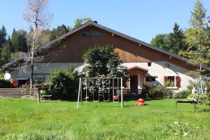 a playground in front of a house with a barn at Ancienne petite ferme in Châtelblanc