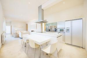 a white kitchen with a white table and chairs at Casa Con Piscina En Selva in El Port de la Selva