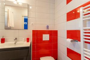 ein rot-weißes Badezimmer mit Waschbecken und Toilette in der Unterkunft Chambre - Gentiane in Aroue