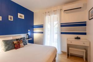 ein blau-weißes Schlafzimmer mit Bett und Fenster in der Unterkunft Chambre - Gentiane in Aroue