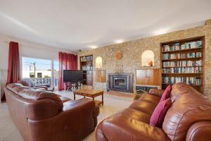 a living room with two leather couches and a fireplace at Brisa do Mar in Carvoeiro