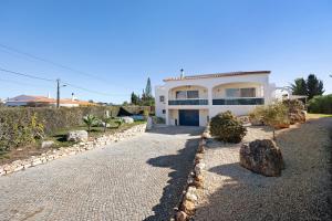 a large white house with a stone driveway at Brisa do Mar in Carvoeiro