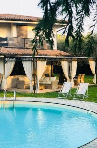 a pool in front of a house with two lawn chairs at Villa Grazia in Manerba del Garda
