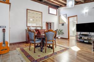 a dining room with a table and chairs and a guitar at Camere La Ro Ca- Telti in Telti