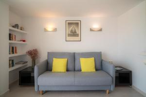 a living room with a blue couch with two yellow pillows at Mirada I in Es Pujols