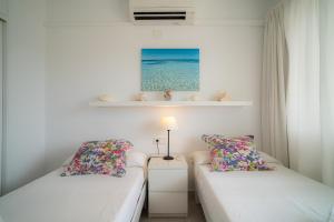 a bedroom with two beds and a table with a lamp at Mirada I in Es Pujols