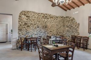 a restaurant with wooden tables and chairs and a stone wall at Il Borghetto Bed and Breakfast in Borgo San Lorenzo