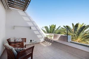 a balcony with two chairs and a table and palm trees at Los Molinos 4306 in Costa Teguise