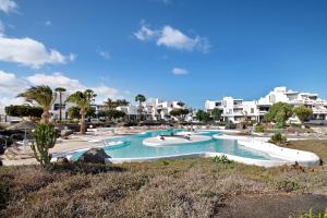 a swimming pool in a resort with buildings in the background at Los Molinos 4306 in Costa Teguise