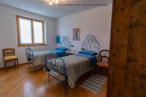 a bedroom with two beds and a table and chairs at Villa Archi in Colico