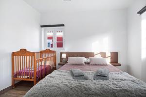 a bedroom with a large bed and a crib at Casa da Padaria in Leiria