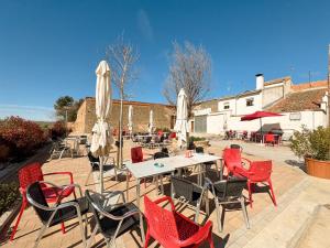 a patio with red chairs and tables and umbrellas at Casa rural La abuela in Mainar