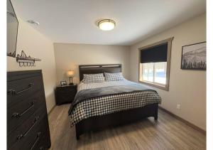 a bedroom with a bed and a dresser and a window at Sunny Peaks in Valemount