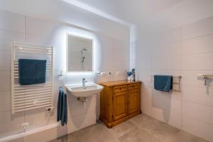 a white bathroom with a sink and a mirror at Ferienwohnung Max in Gilching +14 photos