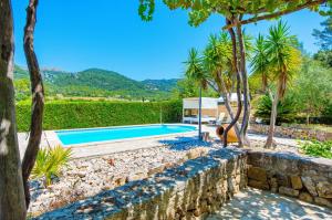 an outdoor swimming pool with trees and a stone wall at Na Garrovera in Pollença