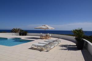 a patio with chairs and an umbrella and a pool at Villa Es Gallinots in Mahón