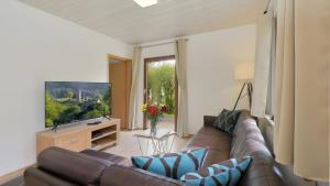 a living room with a couch and a television at Waldfee - Stilvolles Ferienhaus in Kemmerode
