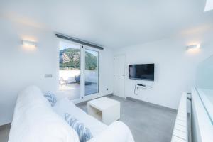 a white living room with a white couch and a tv at Casa Coronel Aloy in Pollença