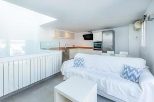 a living room with a white couch and a kitchen at Casa Coronel Aloy in Pollença