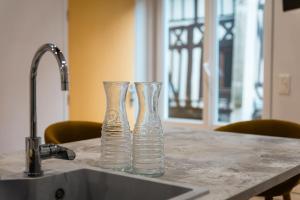 two glass vases sitting on a counter next to a sink at Murmures de la Risle in Pont-Audemer