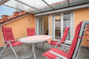 a patio with red chairs and a table on a balcony at Haus Sonnenseite Wohnung Pfänder in Wasserburg