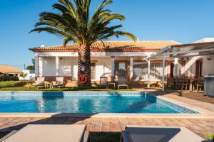 a villa with a palm tree and a swimming pool at Villa Las Rosas in Albufeira