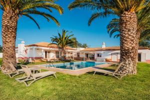 a villa with a swimming pool and two palm trees at Villa Las Rosas in Albufeira