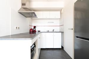 a kitchen with white cabinets and a stainless steel refrigerator at Appartement T2 Muses in Le Crès