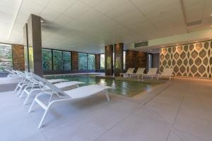 a pool with white lounge chairs and a swimming pool at Appartement T2 Muses in Le Crès