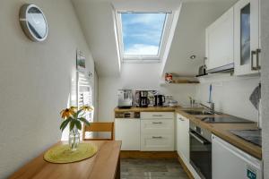 a kitchen with white cabinets and a vase on a table at Ferienwohnung Irmi in Hergensweiler +17 photos