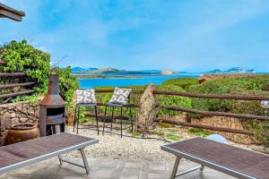a patio with two chairs and a grill and the ocean at Villa Caterina in Punta Molara