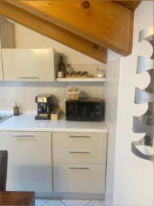 a kitchen with white cabinets and a black microwave at Il Rifugio di Palmanova in Palmanova