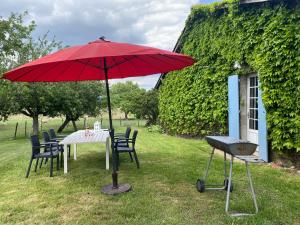 a table with a red umbrella and chairs at Le Gite Du Vigneron Périgord in Razac-de-Saussignac
