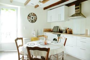 a kitchen with a table with chairs and a clock on the wall at Le Gite Du Vigneron Périgord in Razac-de-Saussignac