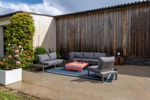 a patio with two couches and a table and chairs at Le Loft avec jacuzzi in Saint-Gildas-de-Rhuys
