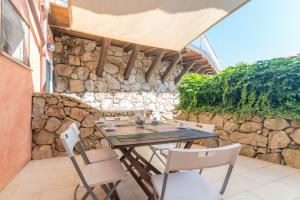 a table and chairs on a patio with a stone wall at C 102 Puntavilla Mare in La Maddalena