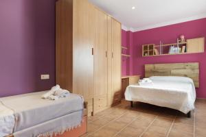 a bedroom with two beds and purple walls at Casa Las Niñas in Olvera