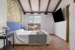 a bedroom with a bed and a tv on the wall at Casa Las Niñas in Olvera