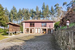 a large pink house with a stone wall at Quinta Da Ataíde in Rendufe