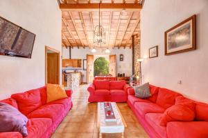 a living room with red couches and a kitchen at Finca Sa Pova in Alcudia