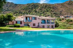 a house with a swimming pool in front of a mountain at 5 Appartamento Isuledda in San Teodoro