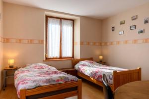 a bedroom with two beds and a window at Le Gîte À Mamie in Orbey