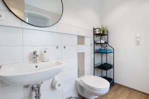 a bathroom with a sink and a toilet and a mirror at Ferienwohung Finsterwalde in Finsterwalde +18 photos