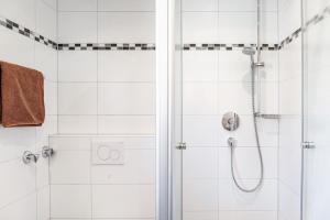 a white bathroom with a shower with a glass door at Alpenblick Tilly - Fewo Soiernsee 4 in Krün +10 photos