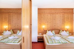 two beds in a room with wooden walls at Alpenblick Tilly - Fewo Soiernsee 4 in Krün