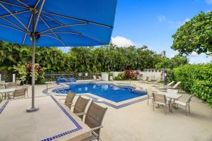 a pool with tables and chairs and an umbrella at NEW Sunset Cove Hale Breathtaking View Pool AC in Princeville