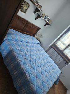 a bedroom with a bed with a blue comforter and a window at Trilocale a Santa Maria Maggiore in Santa Maria Maggiore