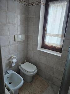 a bathroom with a toilet and a sink and a window at Trilocale a Santa Maria Maggiore in Santa Maria Maggiore +3 photos